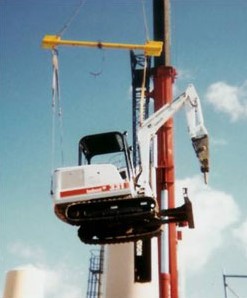 Mini excavator lifted by crane through a roof